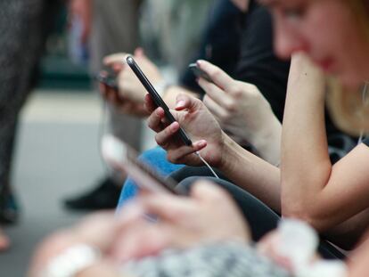 Varias personas consultan sus redes sociales a través de sus teléfonos móviles.