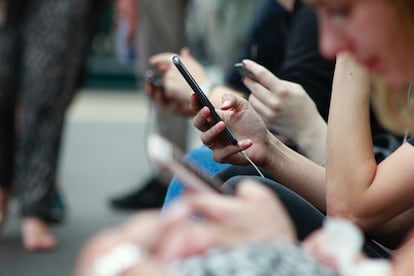 Varias personas consultan sus redes sociales a través de sus teléfonos móviles.