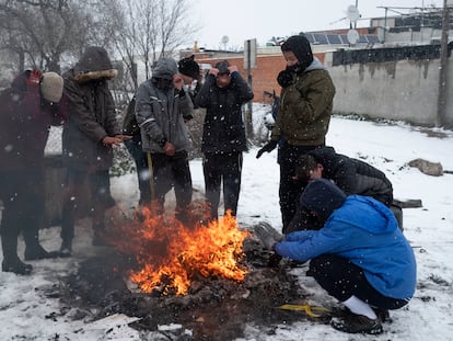 Un grupo de jóvenes se calientan en torno a una hoguera en la Cañada Real durante la nevada Filomena, en enero de 2021.