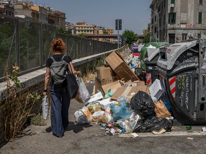 Una mujer camina junto a contenedores de basura desbordados en el barrio del Pigneto de Roma, el 21 de julio.