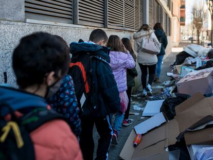 Un grupo de estudiantes pasa en fila por una acera de Salt invadida por bolsas de basura.