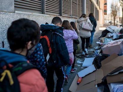 Un grupo de estudiantes pasa en fila por una acera de Salt invadida por bolsas de basura.