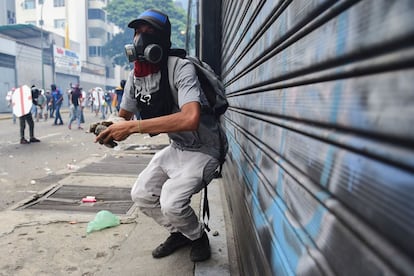 Un manifestante se prepara para lanzar una piedra durante enfrentamientos con la policía antidisturbios en una protesta contra el presidente venezolano Nicolás Maduro, en Caracas.