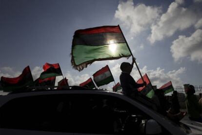 Un joven, sentado sobre el parabrisas de un coche, hace ondear la bandera libia durante una manifestación en Bengasi, el 31 de marzo de 2011.