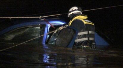 Un bombero intenta acceder al vehículo en el que quedó atrapada una familia en Onda.