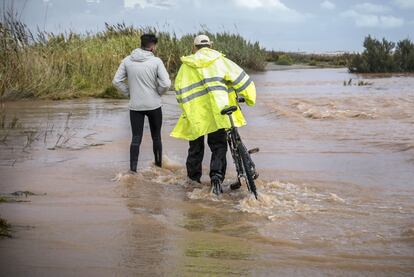 Dos personas pasan por una zona inundada en Sagunto.