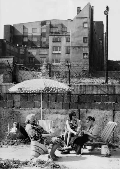 Una familia aprovecha los días soleados para sacar las tumbonas y las sombrillas directamente al lado del muro de Berlín.