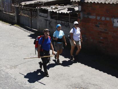 Peregrinos pasan junto a un tramo descuidado del Camino de Santiago en Palas de Rei (Lugo).