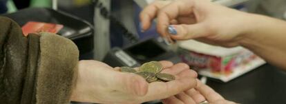 Una cajera ayuda a un cliente a contar las monedas de euro en un supermercado. 