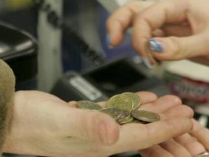 Una cajera ayuda a un cliente a contar las monedas de euro en un supermercado. 