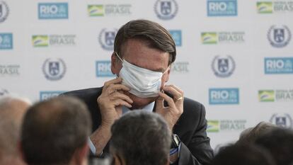 El presidente de Brasil, Jair Bolsonaro, intenta colocarse la mascarilla durante la inauguración de la nueva escuela cívico-militar General Abreu en Río de Janeiro.