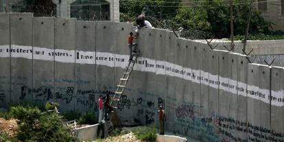 Varias personas intentan saltar el muro en los alrededores de Jerusal&eacute;n.