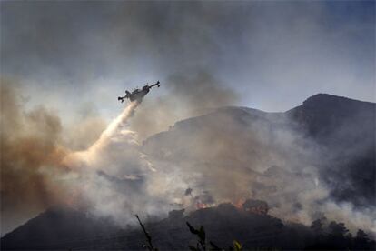 Un avión descargaba ayer agua sobre una pinada en llamas, en el término de Xeraco.