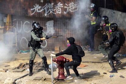 Um policial antidistúrbios aponta contra vários manifestantes durante os protestos na Universidade Politécnica de Hong Kong.