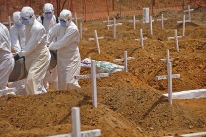Trabajadores sanitarios llevan el cadáver de una víctima de ébola en un nuevo cementerio en las afueras de Monrovia, Liberia.
