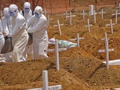 Trabajadores sanitarios llevan el cad&aacute;ver de una v&iacute;ctima de &eacute;bola en un nuevo cementerio en las afueras de Monrovia, Liberia.