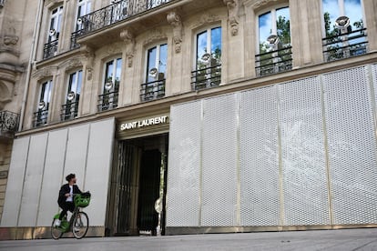Un hombre pasa en bicicleta por los escaparates protegidos de la tienda de Saint Laurent en la avenida de los Campos Elíseos durante la segunda vuelta de las elecciones parlamentarias francesas anticipadas, en París.
