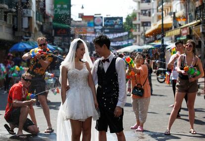 Según cifras oficiales, medio millón de extranjeros visita el país estos días para participar en las celebraciones callejeras ataviados muchos con las típicas camisas de flores, pistolas de agua y polvos de talco o tiza con los que se pintan rostros y brazos (una costumbre adoptada de los polvos usados por los monjes budistas para bendecir). En la imagen, una pareja sonríe mientras varias personas les bañan en agua en una calle de Bangkok.