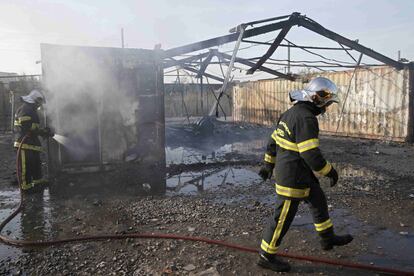 Bomberos cerca de uno de los refugios quemados, después del incendio que destruyó el campo de migrantes, cerca de la frontera belga.