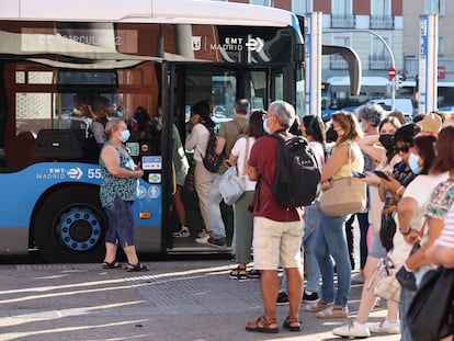 Viajeros con mascarilla esperan para montarse en un autobús municipal de Madrid.