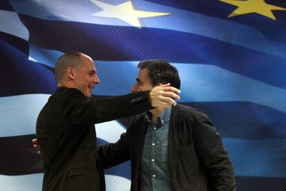 El saliente ministro griego de finanzas Yanis Varoufakis abraza al nuevo ministro Euclides Tsakalotos