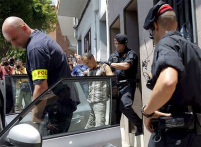 Tres 'mossos' acompañan a uno de los detenidos durante la operación contra las mafias chinas en Mataró