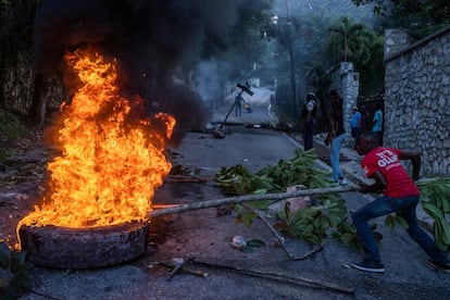 Un hombre empuja un neumático en llamas que se utilizó como barricada en protesta por un reciente secuestro y tiroteo en el barrio de Petionville de Puerto Príncipe, Haití.