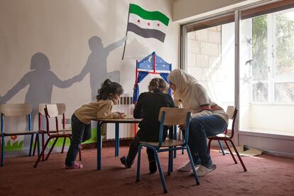 Una voluntaria trabaja con unos niños sirios en la escuela Malki-Salaam de Amman (Jordania). Unos 60 menores huidos de su país por la guerra reciben aquí atención psicológica para superar sus traumas.