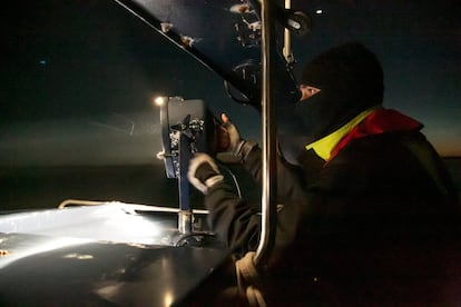 En pleno cauce del río, un miembro del Servicio de Vigilancia Aduanera enciende el foco para iluminar una barca camaronera fondeada en mitad del Guadalquivir que podría esconder un alijo de hachís.