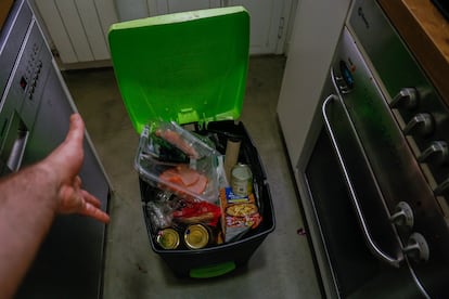 Un hombre tira unos filetes caducados al cubo de basura de su cocina. 