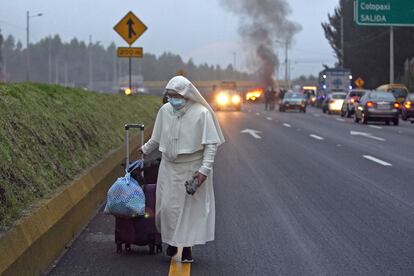 Una monja camina con su equipaje de mano por una carretera bloqueada por indígenas y agricultores en San Juan de Pastocalle, en la provincia ecuatoriana de Cotopaxi.