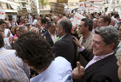 Federico Trillo, detrás de Francisco Camps, hace una peineta a la salida de un acto en Torrevieja.