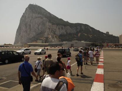 Pedestrians and drivers cross the tarmac of the Gibraltar airport in front of the Rock.