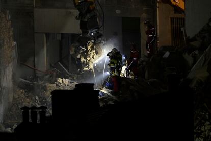 Emergency service personnel watch as an excavator moves rubble at 'rue Tivoli' after a building collapsed in the street, in Marseille, southern France, on April 9, 2023