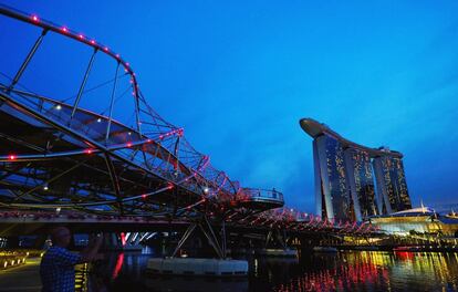 Un hombre toma una foto del Puente Helix, que se conecta con el resort integrado de Marina Bay Sands, al anochecer en el distrito central de negocios de Singapur.