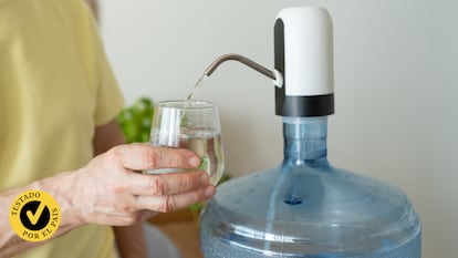 Una persona llenando un vaso con un dispensador de agua.