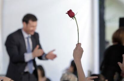 Un asistente sostiene una rosa entre el público que sigue la intervención de Tomás Gómez en la plaza del Dos de Mayo.