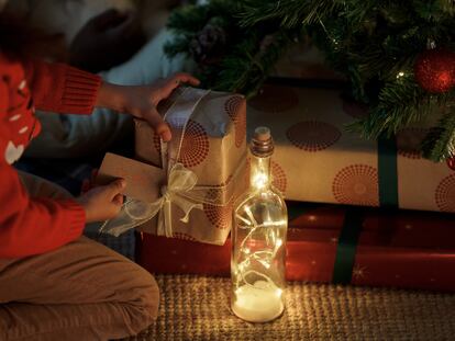 Un niño busca su nombre entre los regalos que han dejado los Reyes Magos bajo el árbol.