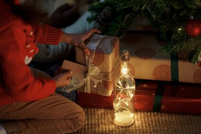 Un niño busca su nombre entre los regalos que han dejado los Reyes Magos bajo el árbol.