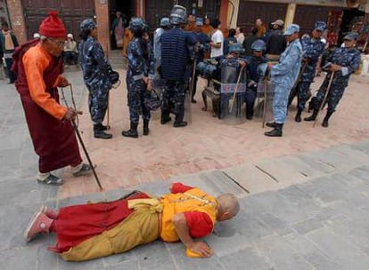 Un monje tibetano reza en presencia de policías nepaleses que vigilan un templo de Katmandú.