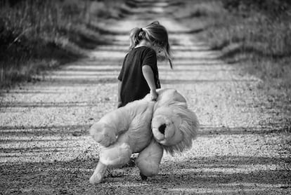 Una niña pasea triste con su oso peluche.