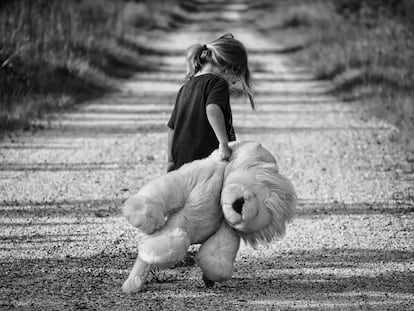 Una niña pasea triste con su oso peluche.