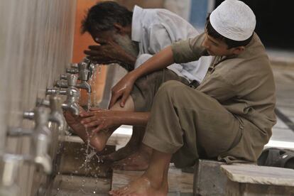 Dois muçulmanos paquistaneses realizam a ‘ablução’ (purificação) durante a oração da primeira sexta-feira do Ramadã em uma mesquita em Peshawar (Paquistão), em 4 de julho de 2014.