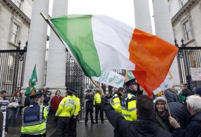 A Sinn Fein protestor waves the Irish tricolor following clashes with police officers after breaking through the gates of Government Buildings in Dublin