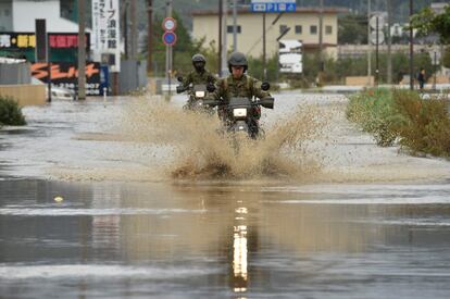 El personal militar conduce sus motos por una calle inundada tras el tifón en Japón, este lunes.