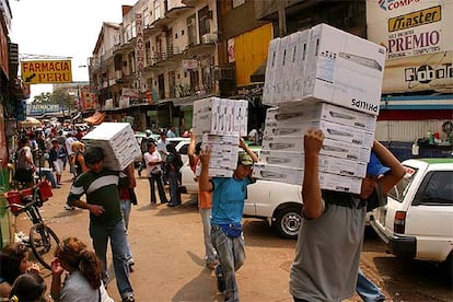 Varias personas cargan cajas con reproductores de DVD en una calle de Ciudad del Este.