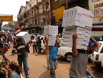 Varias personas cargan cajas con reproductores de DVD en una calle de Ciudad del Este.