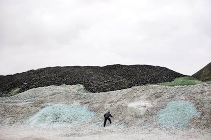 In this Wednesday, Jan. 27, 2016 photo, a worker collects plastic bottles among piles of broken glass, later to be recycled at the Phoenicia Glass Works Ltd. factory in the southern Israeli town of Yeruham. Phoenicia Glass Works Ltd., Israelx92s only glass container factory, produces one million containers a day. Some 300,000 bottles a day come out with defects, and the factory grinds them into shards and piles them in a desert lot to be melted into new bottles. The factory is in the middle of the desert, and works round the clock, every day of the year. (AP Photo/Oded Balilty)