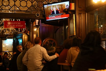 Varios clientes de un pub atienden al discurso del primer ministro británico.