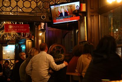Varios clientes de un pub atienden al discurso del primer ministro británico.